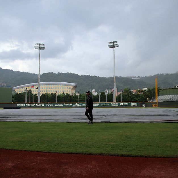 天母棒球場下起驟雨，工作人員已將內野舖上帆布。（林志儒／攝）